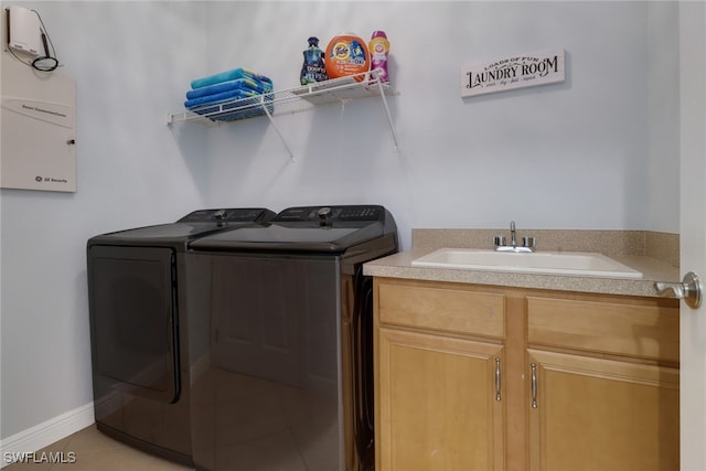 clothes washing area featuring sink, cabinets, light tile patterned floors, and independent washer and dryer