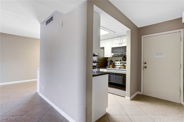 kitchen with white cabinets, light tile patterned floors, and white appliances