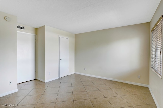 tiled empty room featuring a textured ceiling