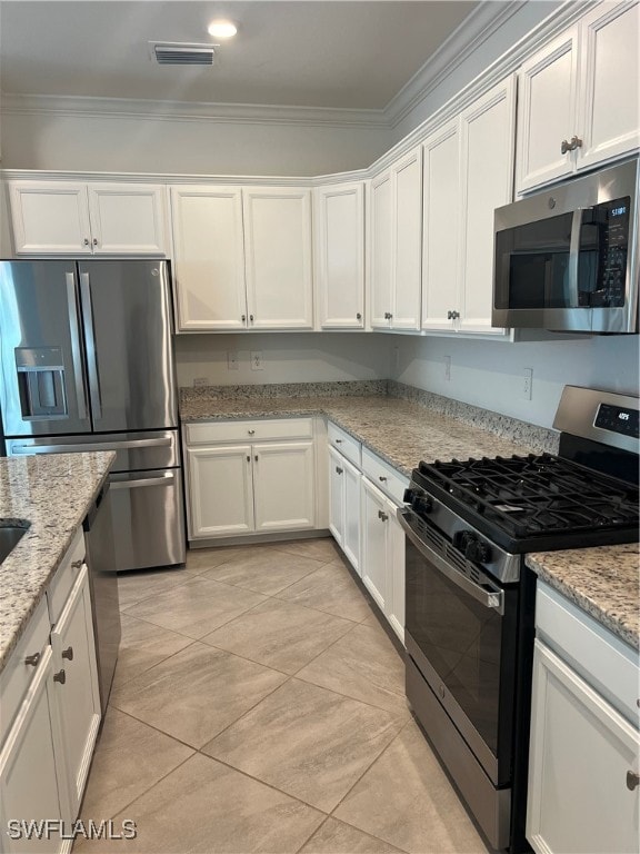 kitchen with light stone countertops, appliances with stainless steel finishes, white cabinetry, ornamental molding, and light tile patterned floors