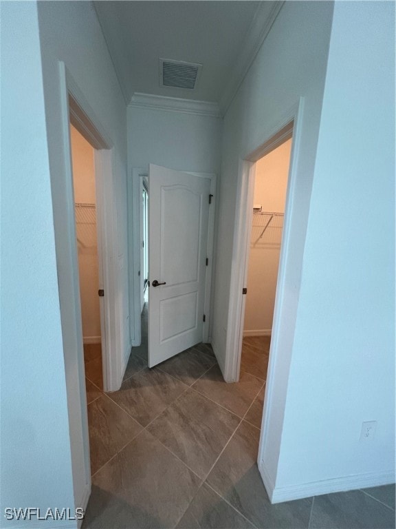 corridor featuring crown molding and dark tile patterned floors