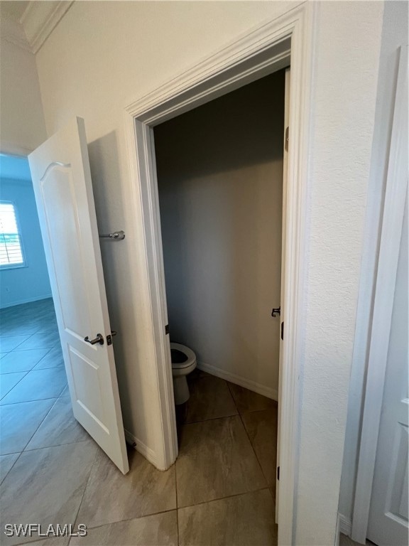 bathroom featuring toilet, ornamental molding, and tile patterned floors