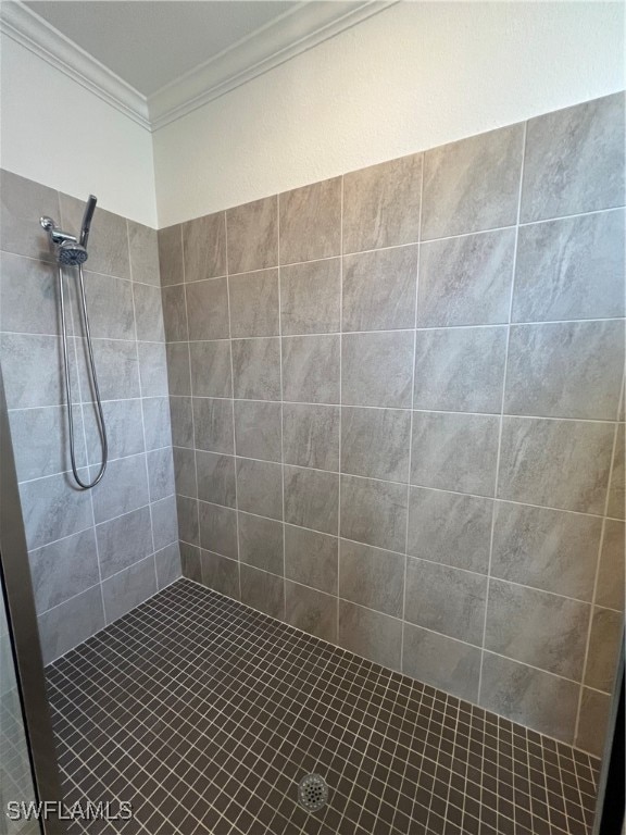 bathroom with tiled shower and ornamental molding