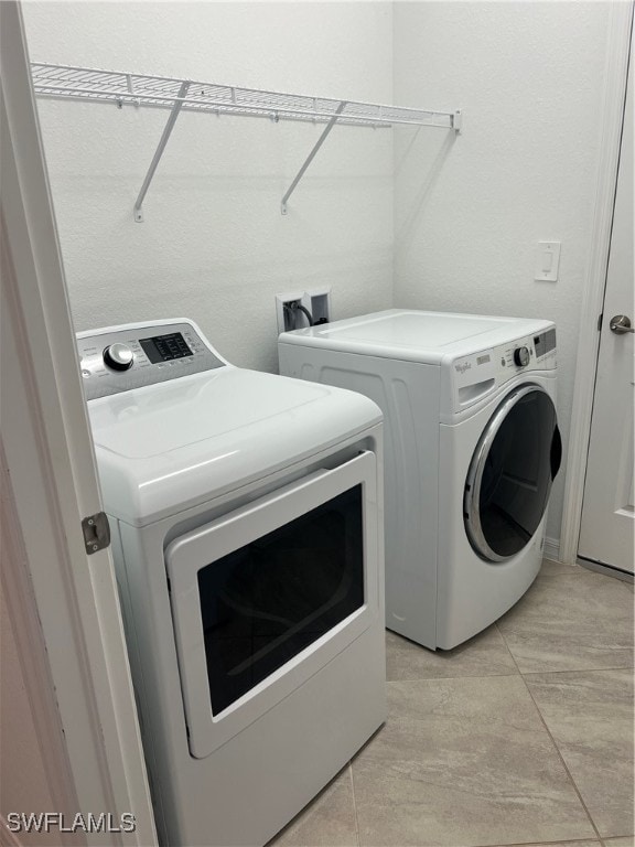 clothes washing area featuring separate washer and dryer and light tile patterned floors