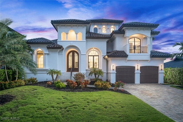 mediterranean / spanish-style house with a garage, a yard, and a balcony