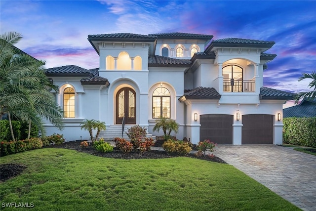 mediterranean / spanish home featuring a garage, a lawn, and a balcony