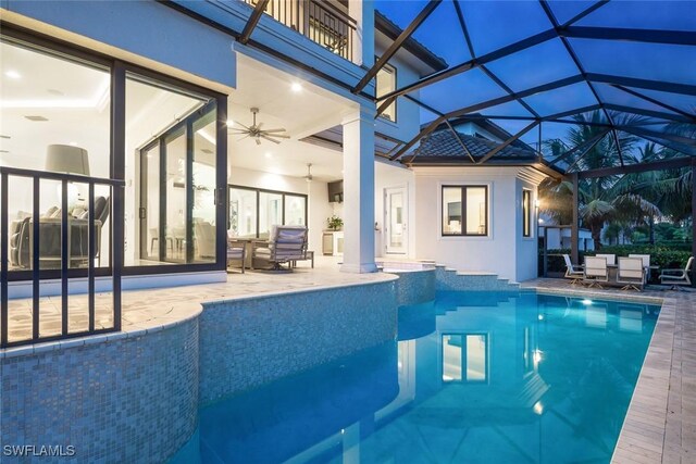 view of pool with glass enclosure, ceiling fan, and a patio area