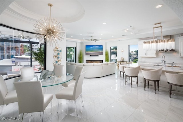 dining area with crown molding, a tray ceiling, and ceiling fan with notable chandelier