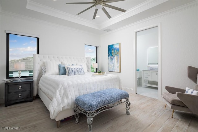 bedroom featuring crown molding, a tray ceiling, light hardwood / wood-style floors, and multiple windows