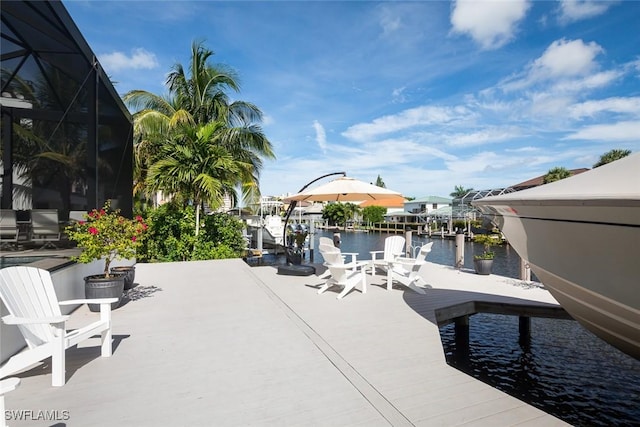 view of patio with a dock, glass enclosure, and a water view