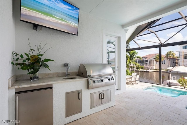 view of patio / terrace with area for grilling, a grill, sink, and a water view