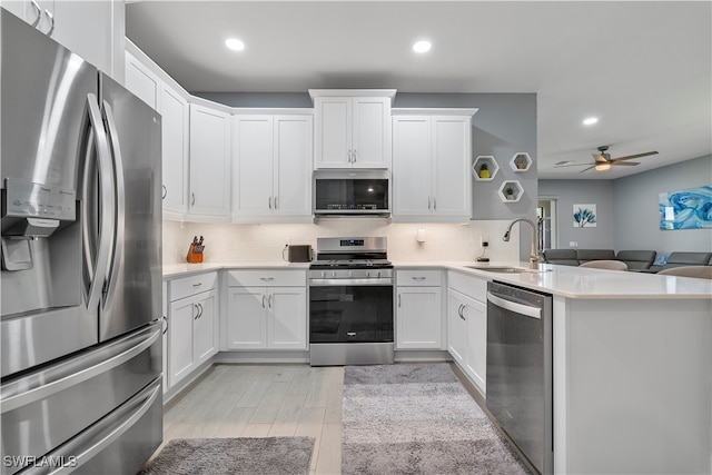 kitchen with appliances with stainless steel finishes, sink, kitchen peninsula, decorative backsplash, and ceiling fan