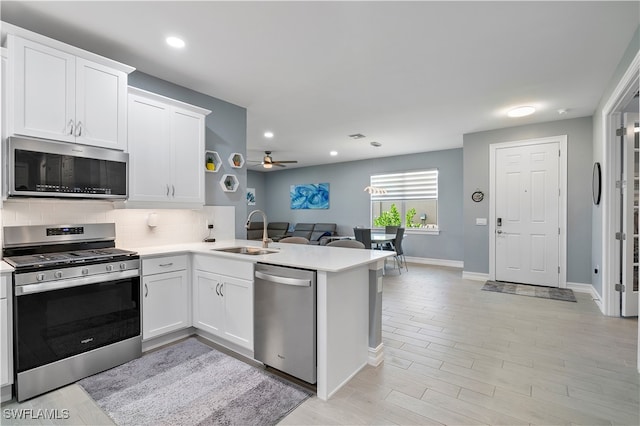 kitchen featuring ceiling fan, stainless steel appliances, decorative backsplash, sink, and kitchen peninsula