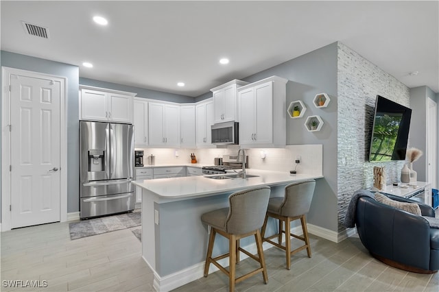 kitchen with white cabinets, appliances with stainless steel finishes, a kitchen bar, and kitchen peninsula