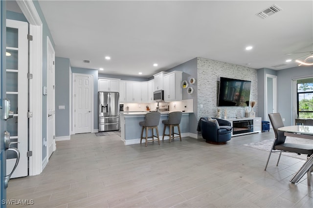 kitchen featuring white cabinetry, appliances with stainless steel finishes, a kitchen bar, and kitchen peninsula