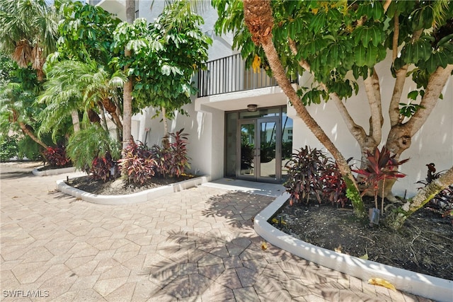 view of exterior entry featuring a balcony and french doors