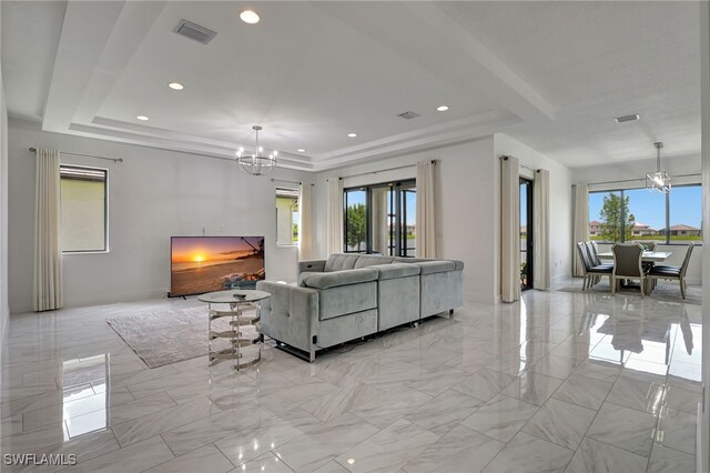 living room featuring light tile patterned flooring, an inviting chandelier, a tray ceiling, and plenty of natural light