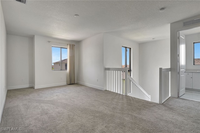 carpeted empty room featuring a textured ceiling