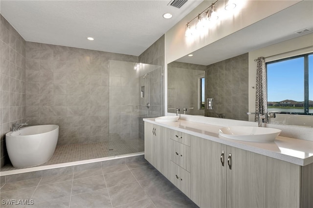 bathroom with tile walls, vanity, a textured ceiling, tile patterned floors, and separate shower and tub