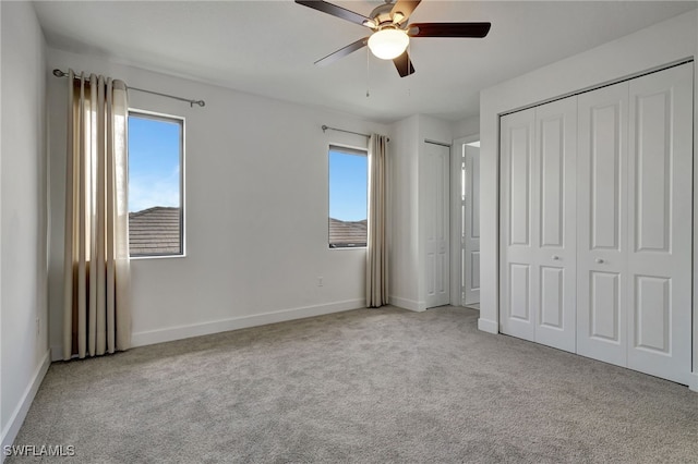 unfurnished bedroom with multiple windows, two closets, light colored carpet, and ceiling fan