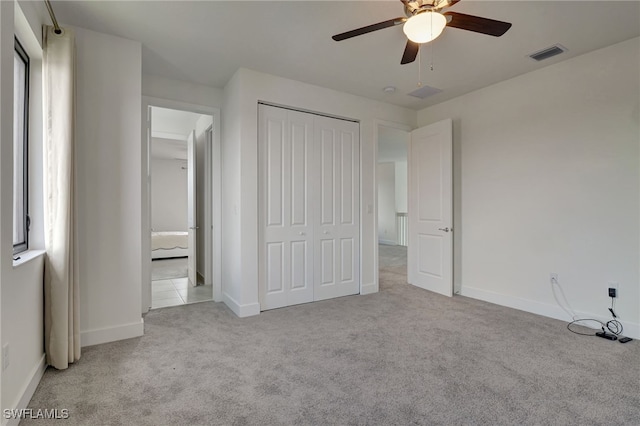 unfurnished bedroom featuring light colored carpet, ceiling fan, and a closet