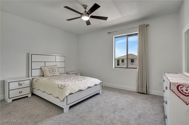 bedroom with ceiling fan, light carpet, and a textured ceiling