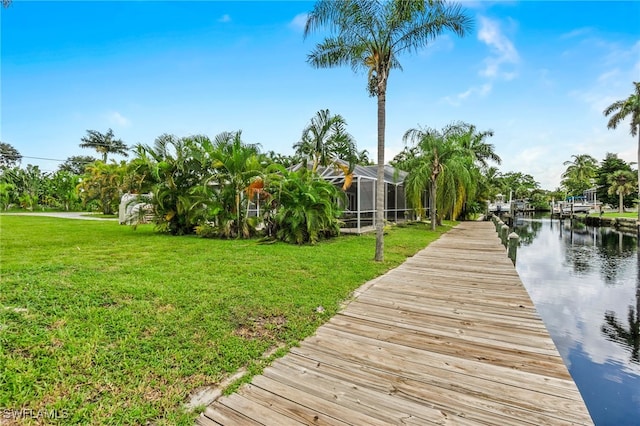 dock area featuring a water view, a yard, and glass enclosure