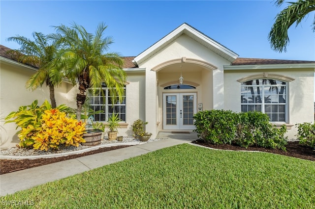 view of exterior entry with a lawn and french doors