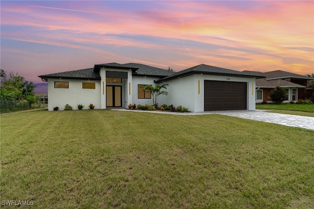 prairie-style home with a garage and a yard