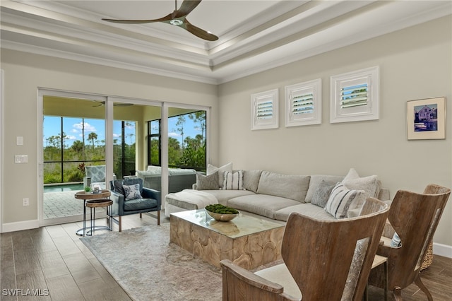 living room with hardwood / wood-style flooring, a raised ceiling, ceiling fan, and ornamental molding