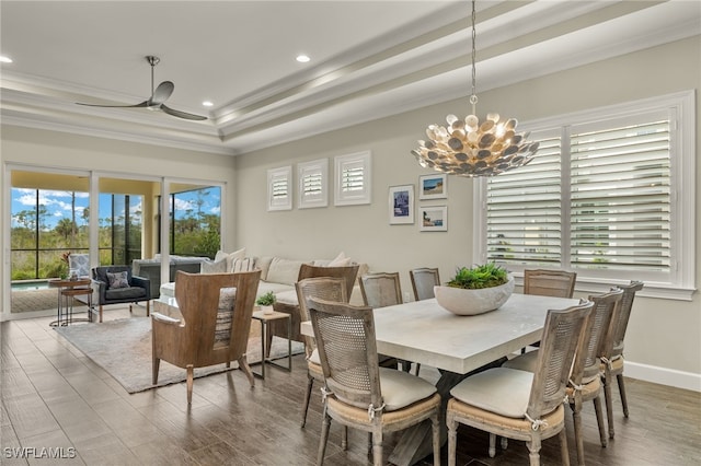 dining space featuring a tray ceiling, crown molding, hardwood / wood-style floors, and ceiling fan with notable chandelier