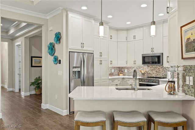 kitchen featuring kitchen peninsula, white cabinets, stainless steel appliances, and decorative light fixtures