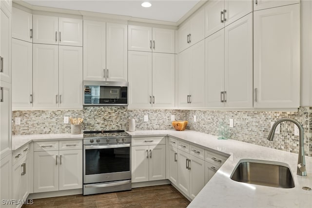 kitchen featuring backsplash, light stone counters, stainless steel appliances, sink, and white cabinetry