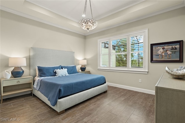 bedroom with a tray ceiling, dark wood-type flooring, a chandelier, and ornamental molding