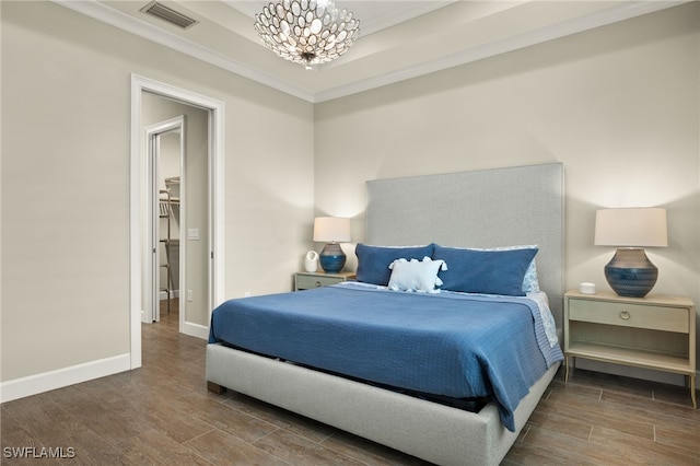 bedroom featuring a tray ceiling, crown molding, and a notable chandelier