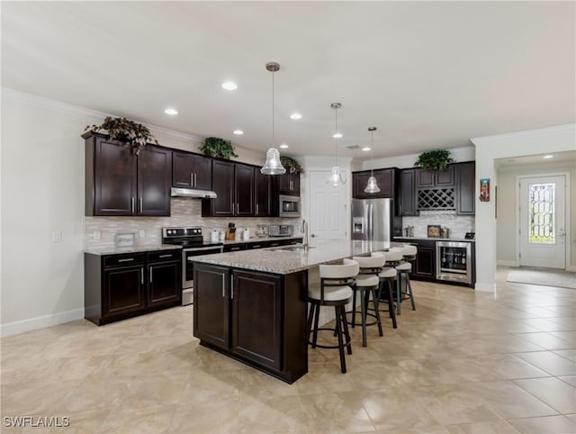 kitchen with sink, decorative light fixtures, dark brown cabinets, appliances with stainless steel finishes, and a kitchen island with sink