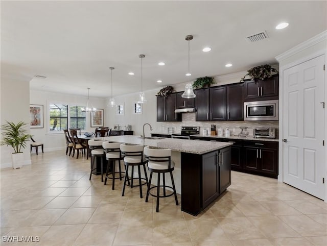 kitchen featuring sink, a breakfast bar, stainless steel appliances, a center island with sink, and decorative light fixtures