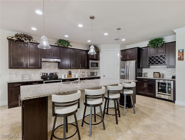 kitchen featuring sink, a kitchen island with sink, hanging light fixtures, stainless steel appliances, and wine cooler