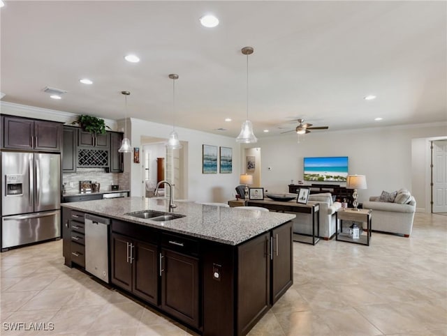 kitchen with sink, hanging light fixtures, stainless steel appliances, dark brown cabinetry, and an island with sink