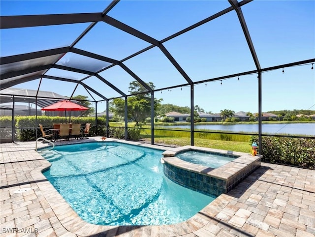 view of pool featuring pool water feature, a patio area, a water view, glass enclosure, and an in ground hot tub