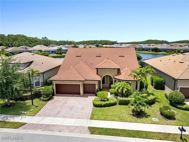 view of front of property featuring a garage, a front yard, and a water view