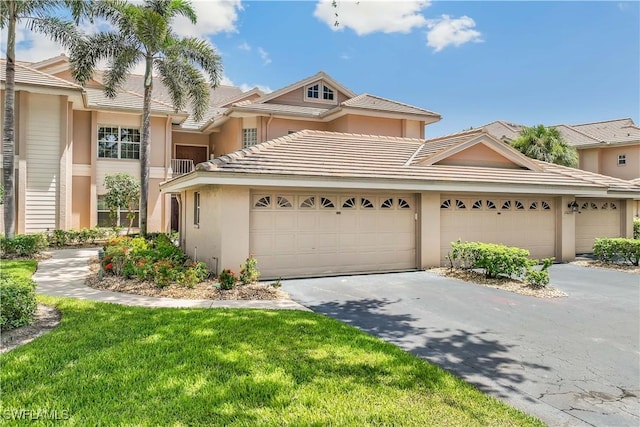 view of property with stucco siding, driveway, a front lawn, and an attached garage