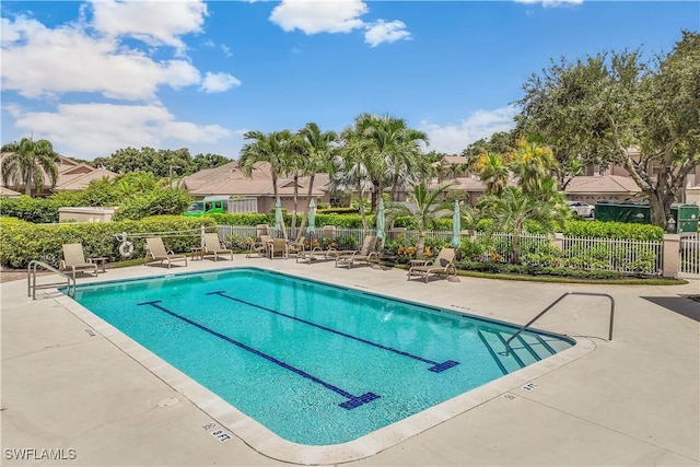 pool with a patio area and fence