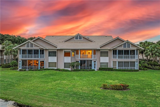 rear view of house featuring a lawn and a sunroom