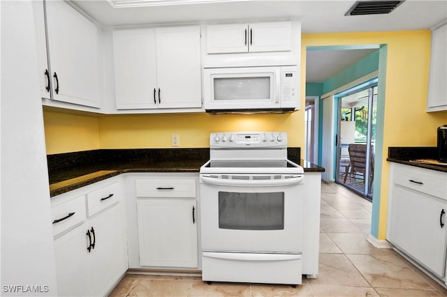 kitchen featuring white appliances, white cabinetry, and dark stone counters