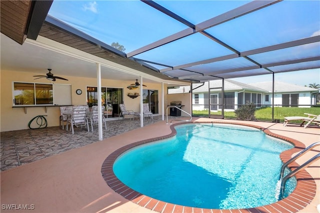 view of pool featuring glass enclosure, ceiling fan, and a patio area