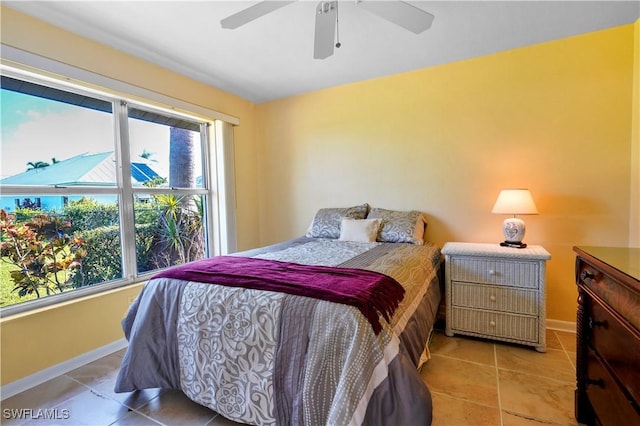 bedroom with ceiling fan, light tile patterned floors, and multiple windows