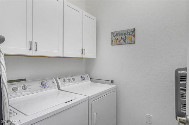 clothes washing area with cabinets and washer and dryer