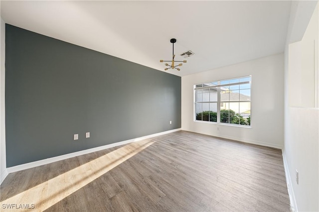 unfurnished room with hardwood / wood-style flooring and a chandelier