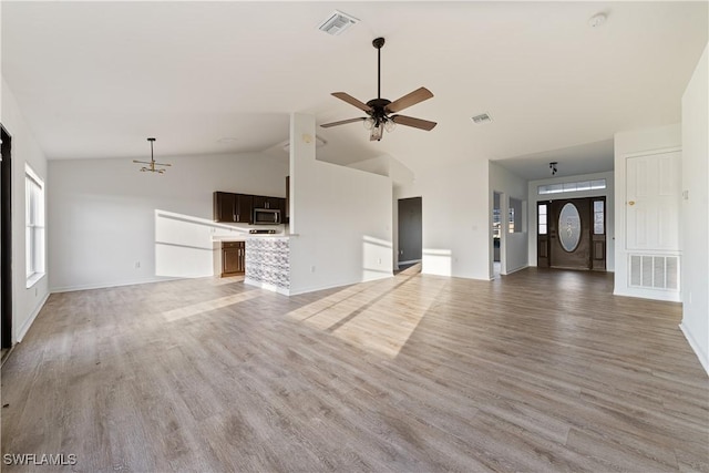 unfurnished living room with ceiling fan with notable chandelier, light hardwood / wood-style flooring, and high vaulted ceiling